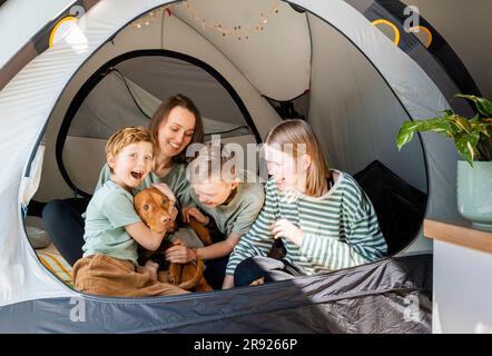 Happy family with Vizsla dog playing in tent at home Stock Photo