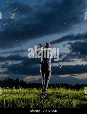 Man playing golf standing on grass facing sky at dusk Stock Photo
