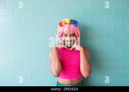 Smiling man wearing pink wig standing in front of wall Stock Photo