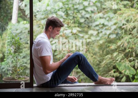 Happy young man using smart phone at home Stock Photo