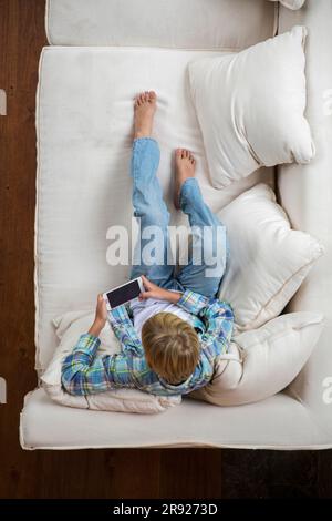 Boy using smart phone on sofa at home Stock Photo