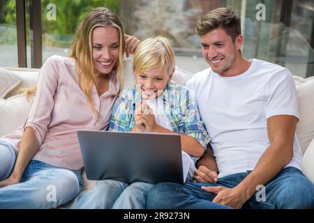 Happy father and mother with son using laptop at home Stock Photo