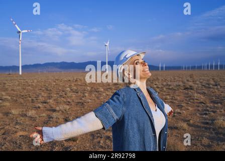 Smiling engineer looking at sky with arms outstretched standing in desert Stock Photo