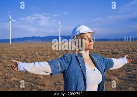 Engineer with arms outstretched and eyes closed standing in desert Stock Photo