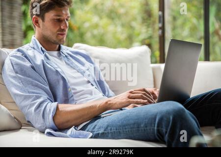Young freelancer typing and working on laptop at home Stock Photo