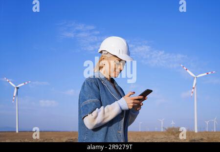Engineer using smart phone standing in desert Stock Photo