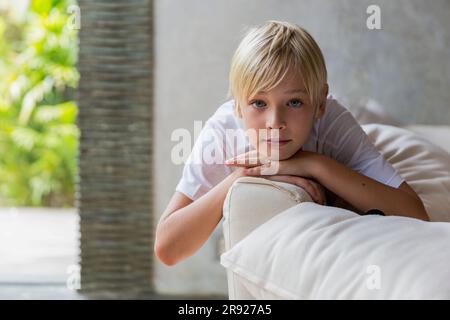 Blond boy lying on sofa at home Stock Photo