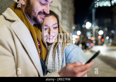 Happy young woman with man using smart phone Stock Photo