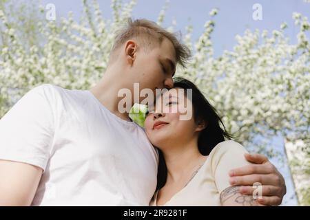 Young man kissing and embracing girlfriend at park Stock Photo
