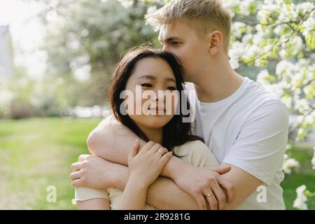 Young man embracing girlfriend at park Stock Photo