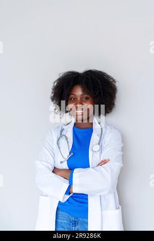 Young Afro doctor with arms crossed standing against white background Stock Photo