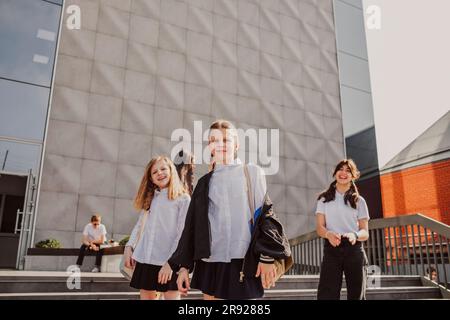 Schoolgirls spending leisure time standing in front of school building Stock Photo