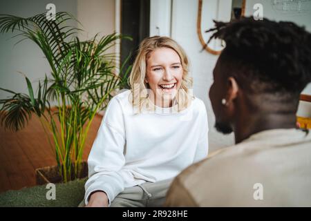 Happy young couple discussing and laughing at home Stock Photo
