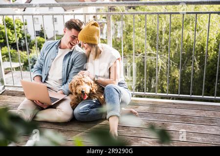 Loving young couple using laptop on balcony Stock Photo