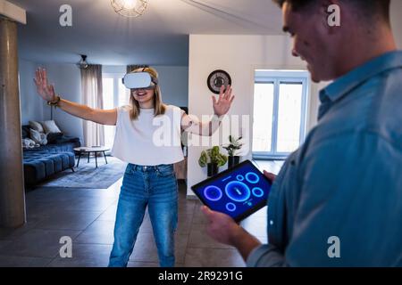 Man using tablet PC with woman wearing virtual reality simulator Stock Photo