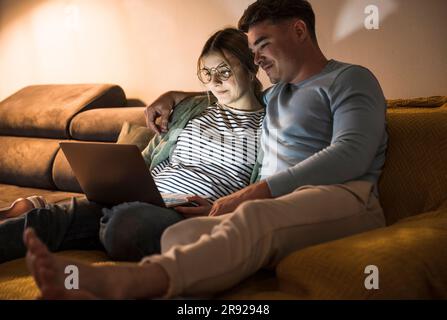 Smiling young couple using laptop together at home Stock Photo