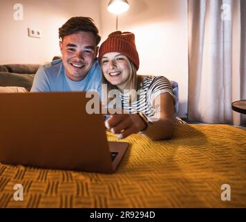 Happy young couple using laptop together at home Stock Photo