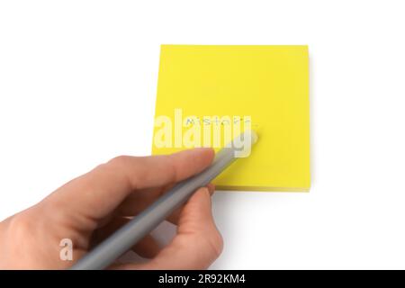 Child erasing word Mistake written with erasable pen on sticky note against white background, closeup Stock Photo