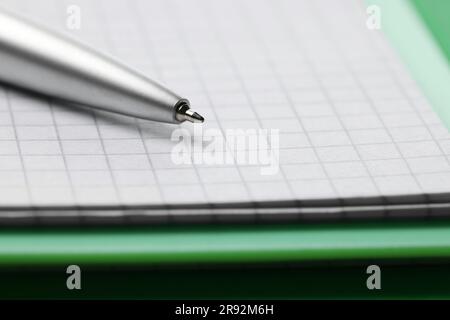 Ballpoint pen and paper sheets on green background, closeup Stock Photo