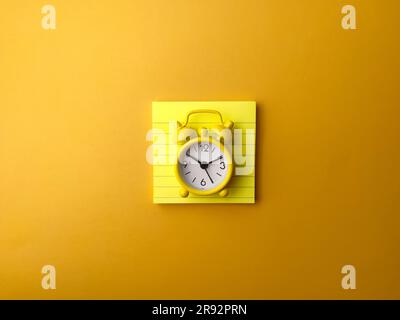 Top view yellow sticky note with alarm clock on a yellow background Stock Photo