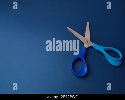 Closeup blue scissors on a blue background with copy space Stock Photo