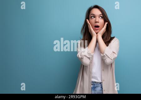 surprised puzzled 30s dark haired woman in shirt and jeans on blue ...