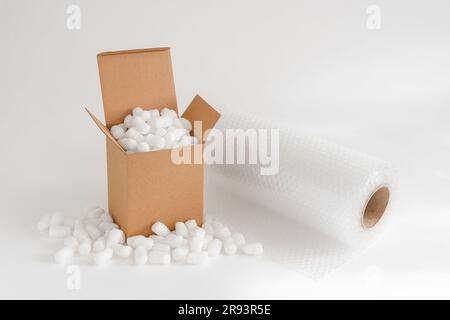 Cardboard box isolated on the white background filled with packing peanuts plus bubble wrap Stock Photo