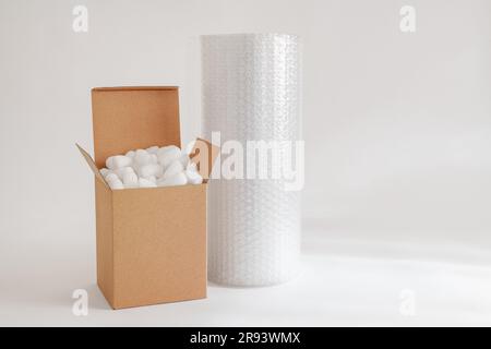 Cardboard box isolated on the white background filled with packing peanuts and bubble wrap Stock Photo