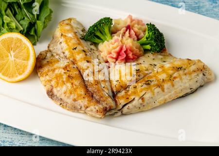 Grilled sea bream fillet with vegetables and greens on wooden table Stock Photo