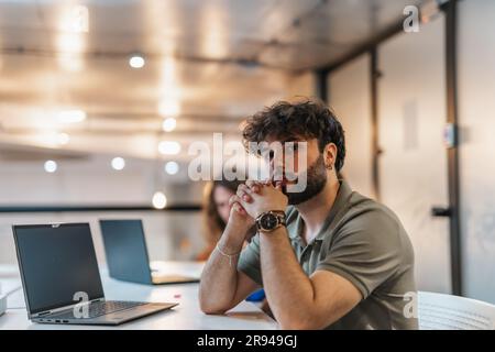 Concentrated male employee listening to his project manager explaining details about his part of the job Stock Photo