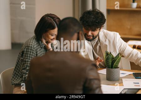 Beautiful, young, multiracial colleagues having fun conversation and smiling while working together Stock Photo