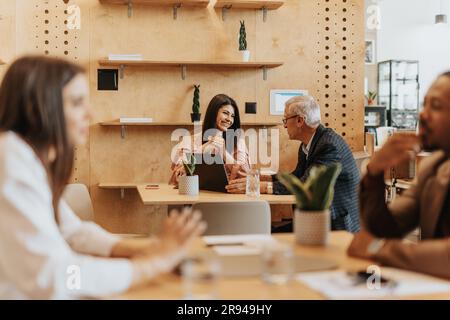 Two businesspeople, young and mature, talking business. Senior businessman telling fun story, brunette businesswoman laughing Stock Photo
