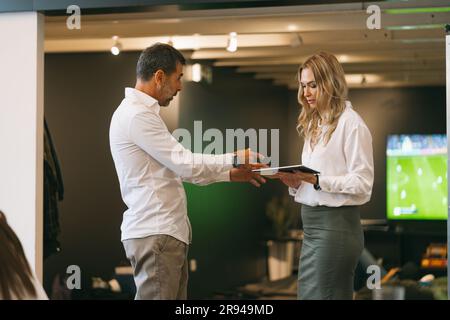 Handsome 50s businessman explaining project details while looking at his partner tablet Stock Photo