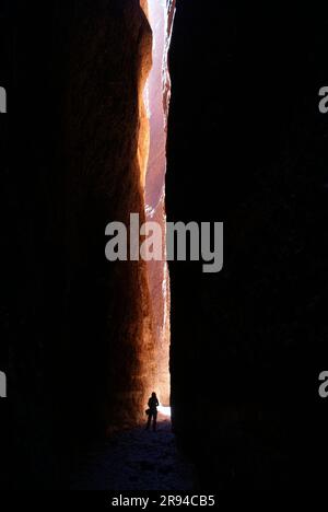 Person standing in the sunbeam shining into the narrow cleft between the rock walls of Echidna Chasm at Purnululu (Bungle Bungles), Western Australia Stock Photo