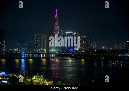 Nighttime view of Saigon River, Ba Son bridge and Vinpearl Landmark 81 building partly covered by the bridge cable tower in Ho Chi Minh city, Vietnam. Stock Photo