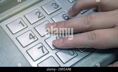 Woman's hand is pressing numbers on keypad to enter verification code in financial transaction. Stock Photo