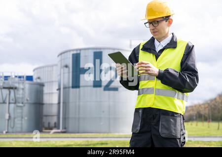 Engineer with tablet computer on a background of Hydrogen factory. High quality photo Stock Photo