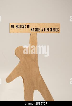 The sentence We believe in making a difference was written. Wooden concept studio shoot. Stock Photo