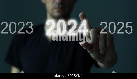 A man touching on virtual screen 2024. Business new year concept, welcome to year 2024 concept. Stock Photo