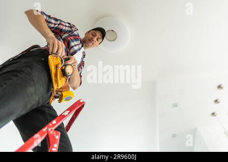 An electrician is installing an LED spotlight in the ceiling Stock ...