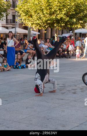 Pamplona, Spain - July, 31: A clown street performer does an upside-down show in the city square with many children watching Stock Photo