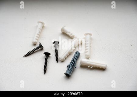 Screws and plastic dowels on a white background. Close-up, top view. Stock Photo