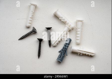 Screws and plastic dowels on a white background. Close-up, top view. Stock Photo