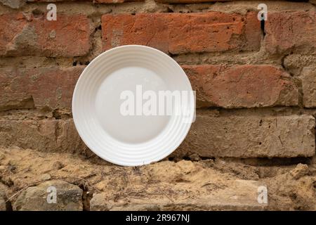 white glass empty plate stands near old brick wall on the street Stock Photo