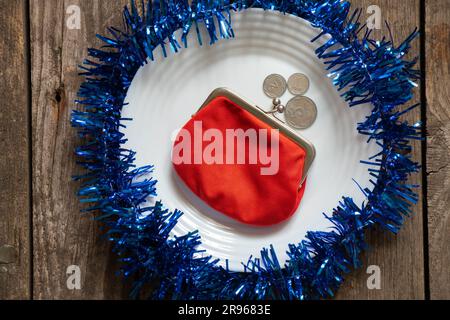 red wallet lies on a white plate decorated New Year's colored ribbon on a wooden background close-up, New Year's decor Stock Photo