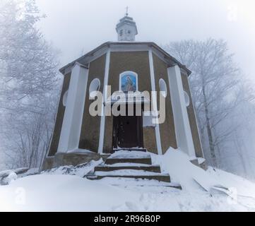 Bardo, Poland - January 2023: Mountain chapel of Our Lady of Weeping in Bardo mountains full of snow and fog at winter Stock Photo