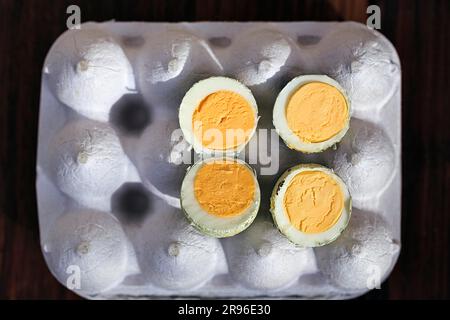 Cooked halved quail eggs on an egg carton, view from above Stock Photo