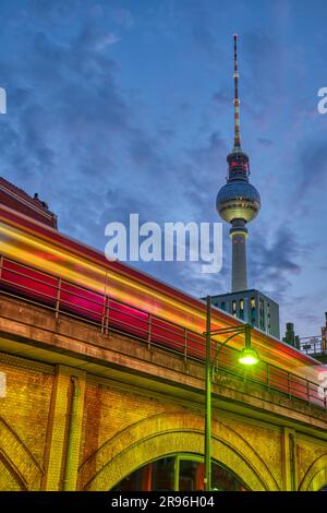 The famous TV tower in Berlin at dusk with a motion blurred local train Stock Photo