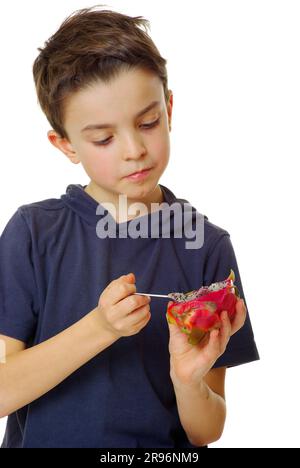 Boy eats pitahaya with triangular hylocereus (Hylocereus triangularis), cactus fruit, dragon fruit, spoon, pitaya Stock Photo