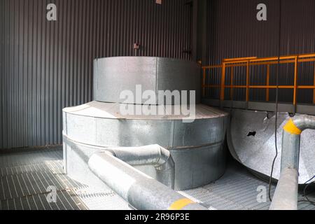 Large iron heat exchanger, tank, reactor, distillation column in thermal insulation of fiberglass and mineral wool of galvanized steel in the industri Stock Photo